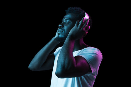 Young African-American man isolated on dark background in neon light