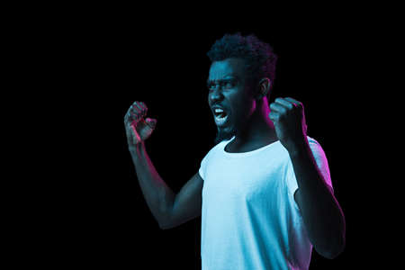 Young African-American man isolated on dark background in neon lightの写真素材