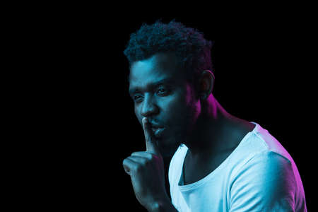Young African-American man isolated on dark background in neon light
