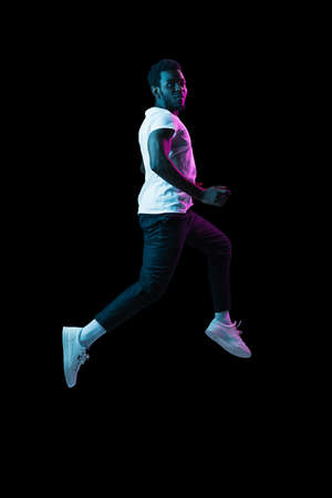 Full-length portrait of young African-American man isolated on dark backgroundの写真素材