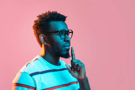 Young serious African-American man isolated on pink background in neon lightの写真素材
