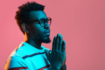 Young serious African-American man isolated on pink background in neon lightの写真素材