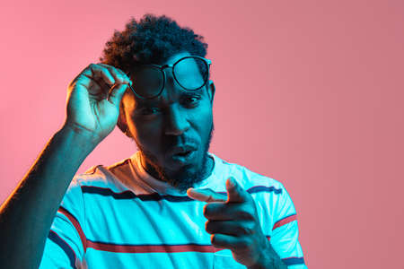 Young African-American man isolated on pink background in neon lightの写真素材