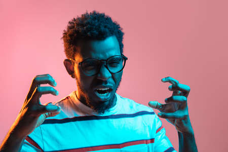 Young African-American man isolated on pink background in neon lightの写真素材