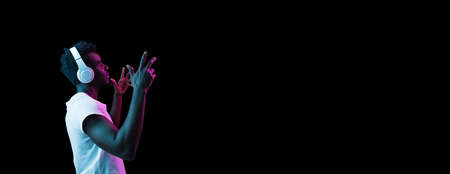 Young African-American man isolated on dark background in neon lightの写真素材