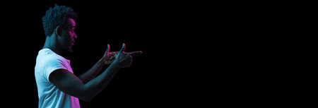 Young African-American man isolated on dark background in neon lightの写真素材