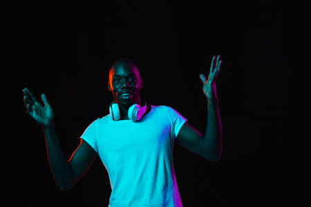 Portrait of young African man isolated on dark background in neon light