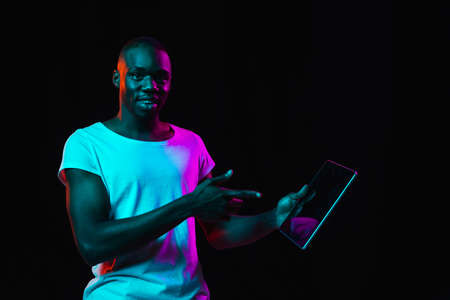 Young African-American man isolated on dark background in neon lightの写真素材