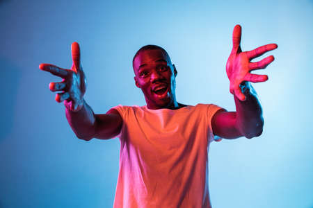One young African-American man isolated on gradient background in neon lightの写真素材