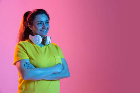 Portrait of beautiful happy woman isolated on pink background in neon light