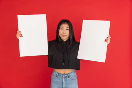 One Asian young girl with blank sheets of paper isolated over red background.の写真素材