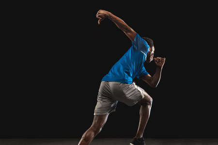 Close-up African-American man, athlete training isolated over black background.