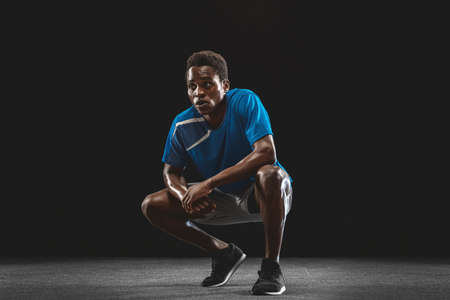 Portrait of young African man, athlete posing isolated over black background.の写真素材