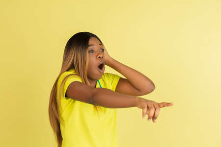 Portrait of African young woman posing isolated on yellow background.