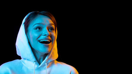 Portrait of young beautiful girl isolated over dark background in neon light.