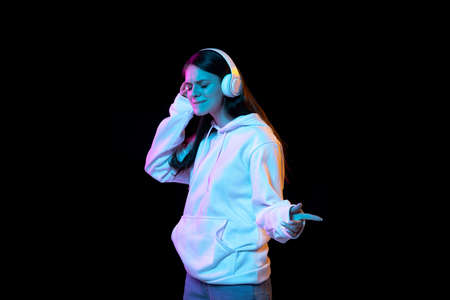 Portrait of young beautiful girl in headphones isolated over dark background.