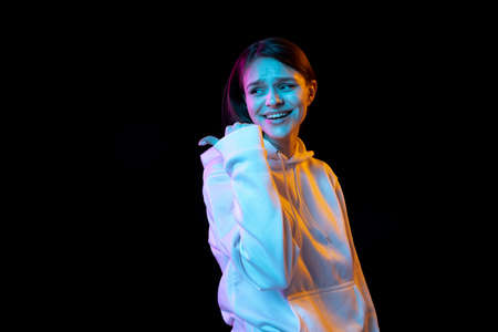 Portrait of young beautiful girl isolated over dark background in neon light.