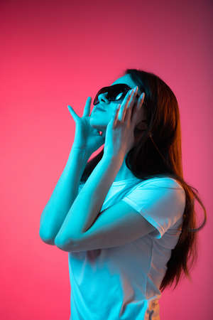 Portrait of young beautiful girl posing isolated over pink background in neon
