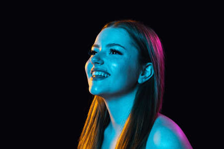 Portrait of young beautiful girl isolated over dark background in neon light.の写真素材
