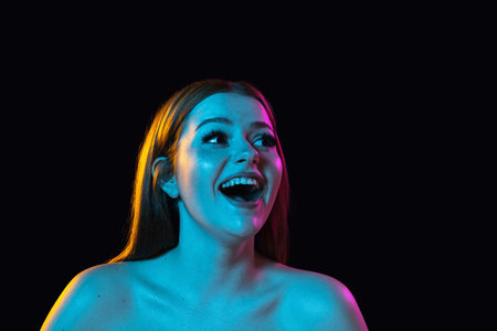 Portrait of young beautiful girl isolated over dark background in neon light.