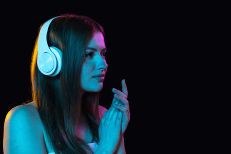 Portrait of young beautiful girl in headphones isolated over dark background.