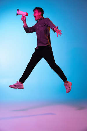 Full length portrait of Asian young man isolated over blue background in neon light
