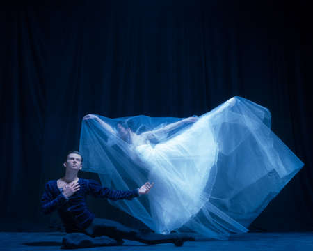 Art performance. Two graceful ballet dancers, man and woman dancing isolated over dark background.