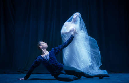 Beautiful graceful woman and man, ballet dancers in art performance dancing isolated over dark backgroundの写真素材