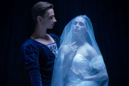 Art performance. Two graceful ballet dancers, man and woman dancing isolated over dark background.