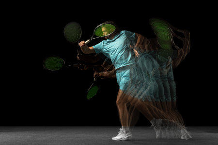 Young Caucasian man, professional tennis player isolated on black background in mixed neon light. Stroboscopeの写真素材