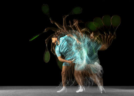 Young Caucasian man, professional tennis player isolated on black background in mixed neon light....