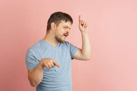 Half-length portrait of young Caucasian man isolated on light pink background. Surprised, wow.の写真素材