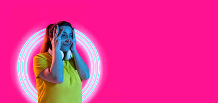 Flyer. One young woman isolated over bright pink magenta background in neon light.の写真素材