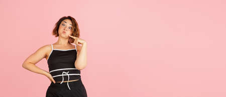 One young Caucasian beautiful woman in black white attire isolated on light pink background.の写真素材