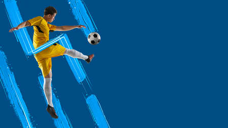 Blue lines. Young man, soccer footbal player kicking the ball isolated in neon light on blue background.の写真素材