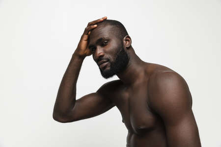 Young handsome muscled African man posing isolated over white background. Concept of beauty, cosmetics, spa.の写真素材