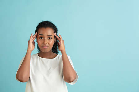 Half-length portrait of young beautiful girl in casual clothes isolated on light blue background.