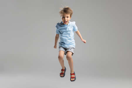 Full-length portrait of Caucasian little boy posing isolated over gray studio background.の写真素材