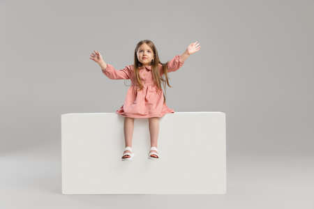 Portrait of little Caucasian cute girl posing isolated over gray studio background.