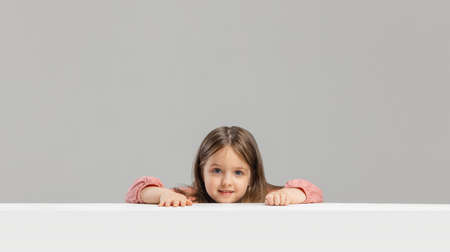 Portrait of little Caucasian cute girl posing isolated over gray studio background.の写真素材