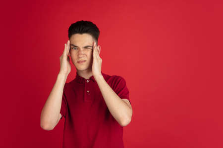 One young Caucasian boy isolated on red studio background. Concept of facial expressions, human...