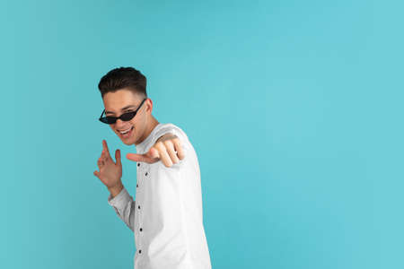 Young Caucasian boy in white shirt isolated on blue studio background. Concept of facial expressions, human emotions.の写真素材