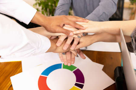 Top view of human hands at office interior. Concept of coworking, work days, support, sales, ad.