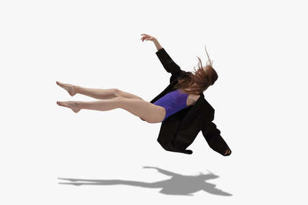 Young beautiful girl, female ballet dancer dancing isolated over white background with shadow.