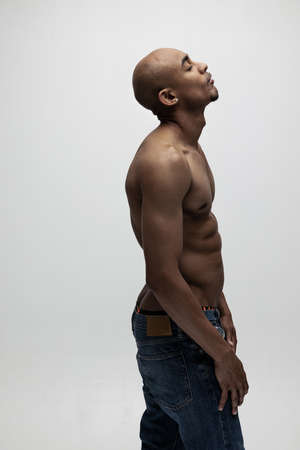 Side view. One young muscled African man posing isolated over white background. Concept of beauty,...
