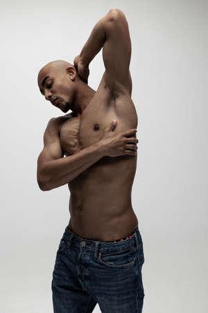 Portrait of young muscled African man, fashion model isolated over white background.