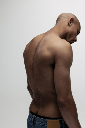 Portrait of young muscled African man, fashion model isolated over white background. Back view