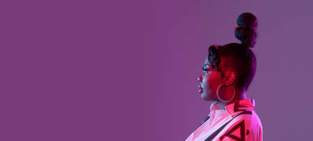 Young beautiful happy African girl isolated on purple background in neon. Flyer