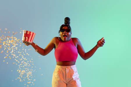 Young beautiful happy African girl isolated on blue-green background in neon.