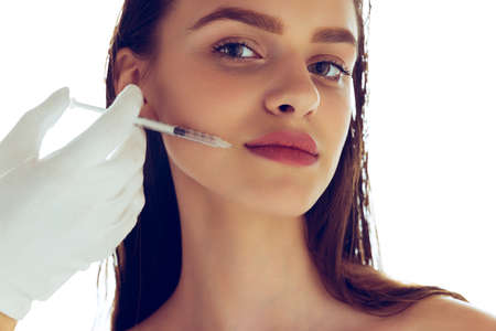 Beauty injections. One beautiful young caucasian girl and a hand with syringe isolated on white...